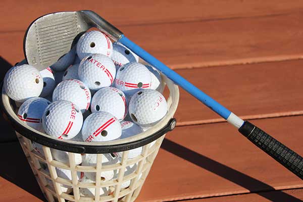 A basket of golf balls and a driver