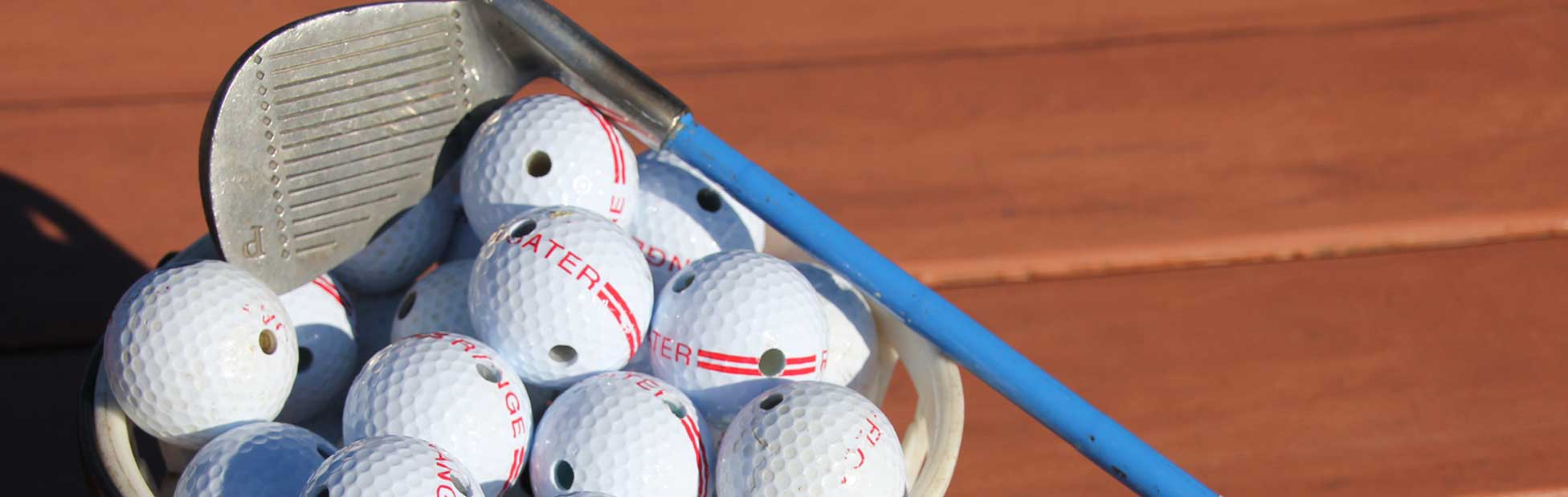 A basket of golf balls and a driver